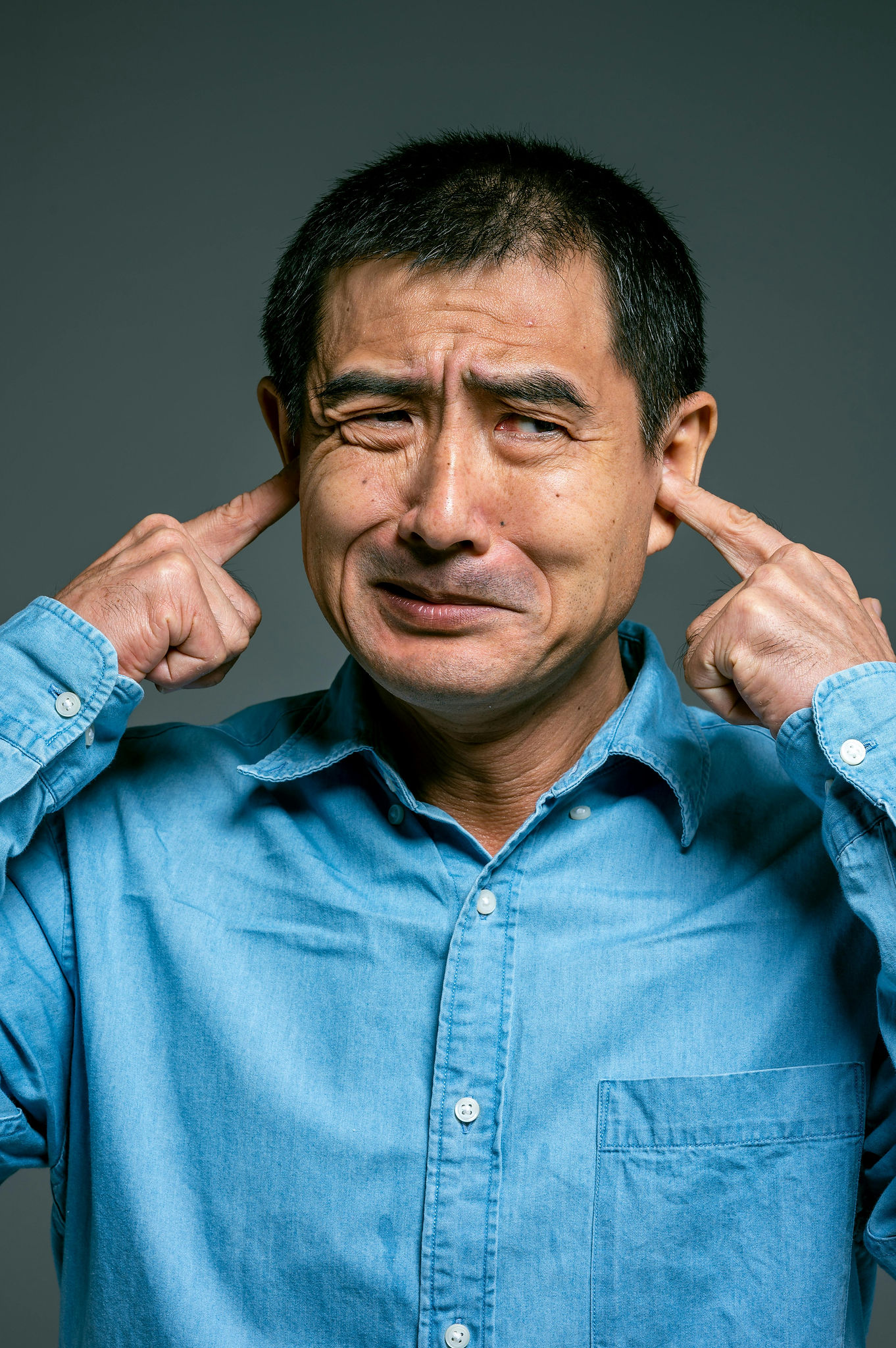 A man plugging his ears with his fingers.